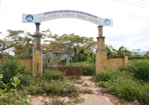 Trường[-]tiểu[-]học[-]A[-]Dơi[-]nhìn[-]từ[-]bên[-]ngoài[-]cỏ[-]mọc[-]um[-]tùm[-]cả[-]lối[-]vào,[-]cổng[-]trưởng[-]bị[-]hư[-]hỏng.[-]Ảnh:[-]Minh[-]Anh